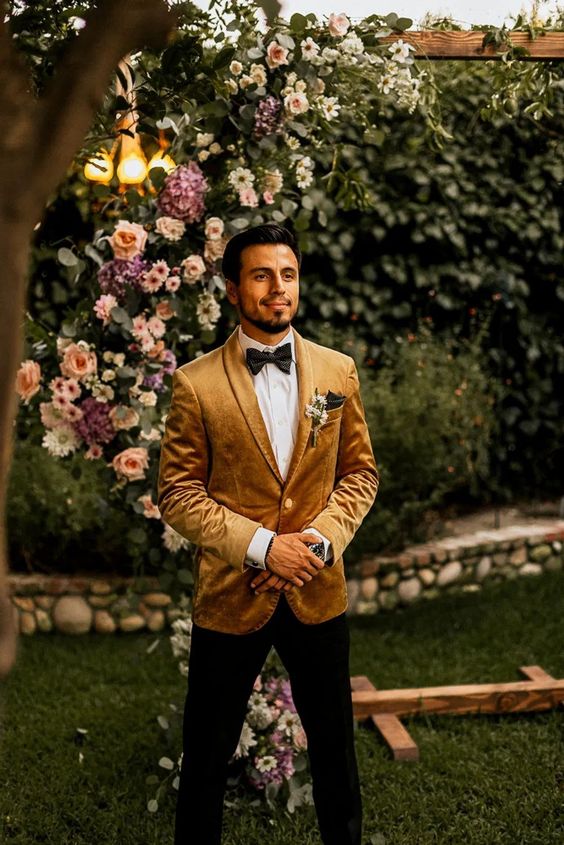 a refined and chic groom's outfit with a mustard velvet blazer, a white shirt, black trousers, a black bow tie for the fall
