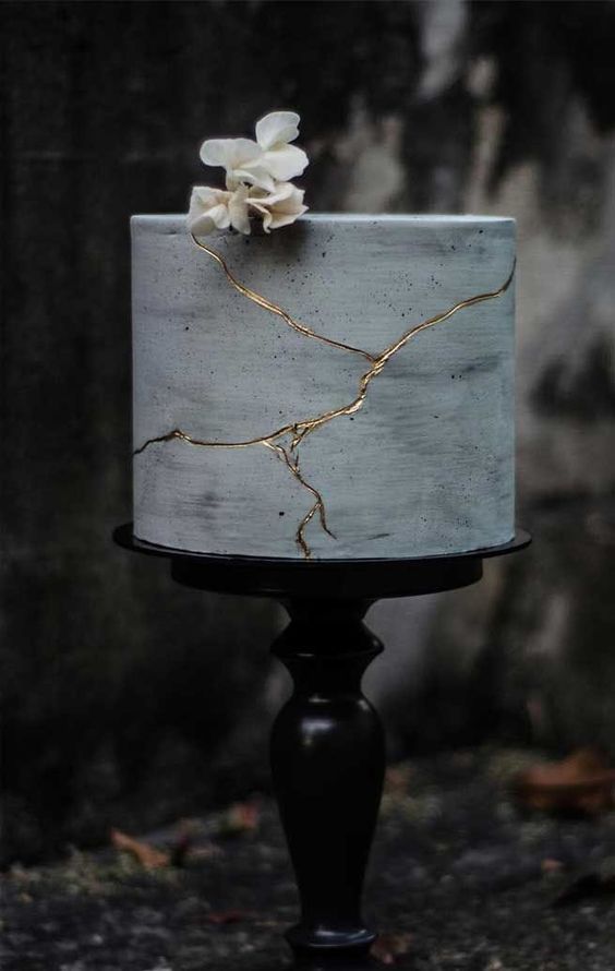 a refined modern wedding cake, a grey concrete one, with gold touches and a white bloom on top is a lovely idea for a modern wedding