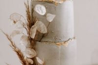 a textured grey wedding cake with a gold edge, dried grasses and lunaria is a stylish and catchy wedding cake