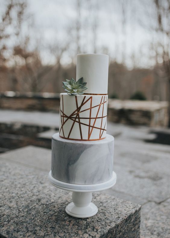a white and grey marble wedding cake with copper touches and a succulent is a cool modern idea