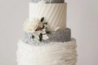 a white and silver wedding cake with silver glitter and patterned tiers and some sugar blooms is a beautiful dessert