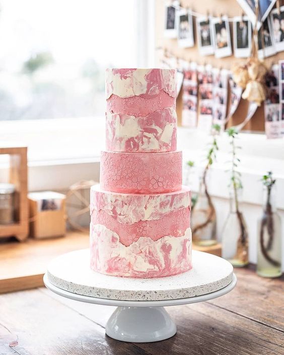 a quirky pink marble wedding cake with fault lines done with matte buttercream and a tier with the same buttercream