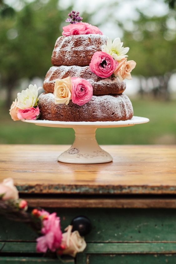 a simple three tier bundt wedding cake with peachy and pink blooms is a relaxed and cool dessert