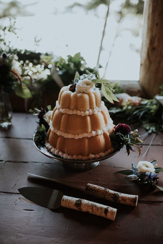 a three tier bundt wedding cake with white and deep purple blooms and greenery is a beautiful idea for a relaxed wedding