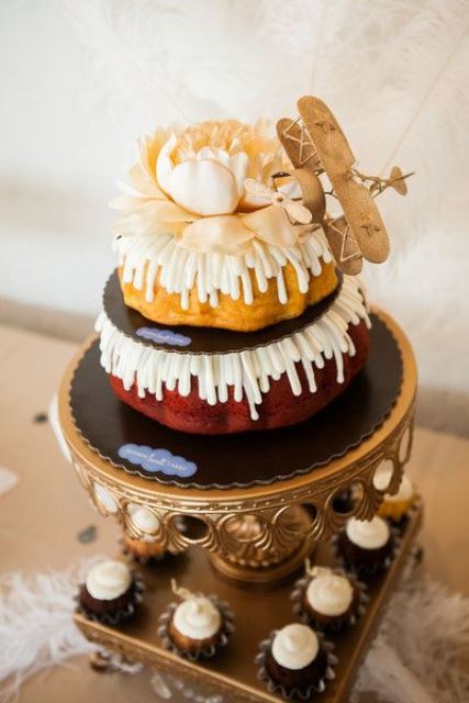 a two-tier bundt wedding cake with creamy drip, a large bloom on top and a lovely airplane for a catchy look