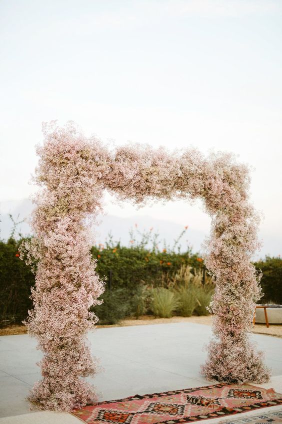 a lush pink baby's breath wedding arch is a pretty and chic idea for a modern wedding and it looks heavenly beautiful