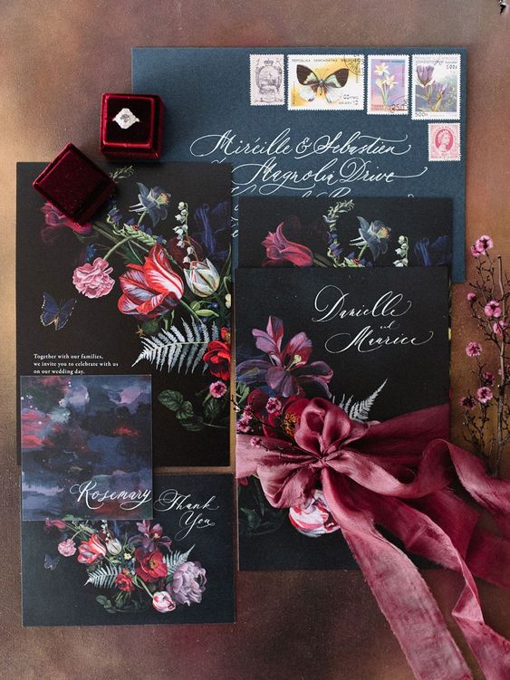 a moody wedding invitation suite in black, grpahite grey and with bold florals and a pink ribbon bow