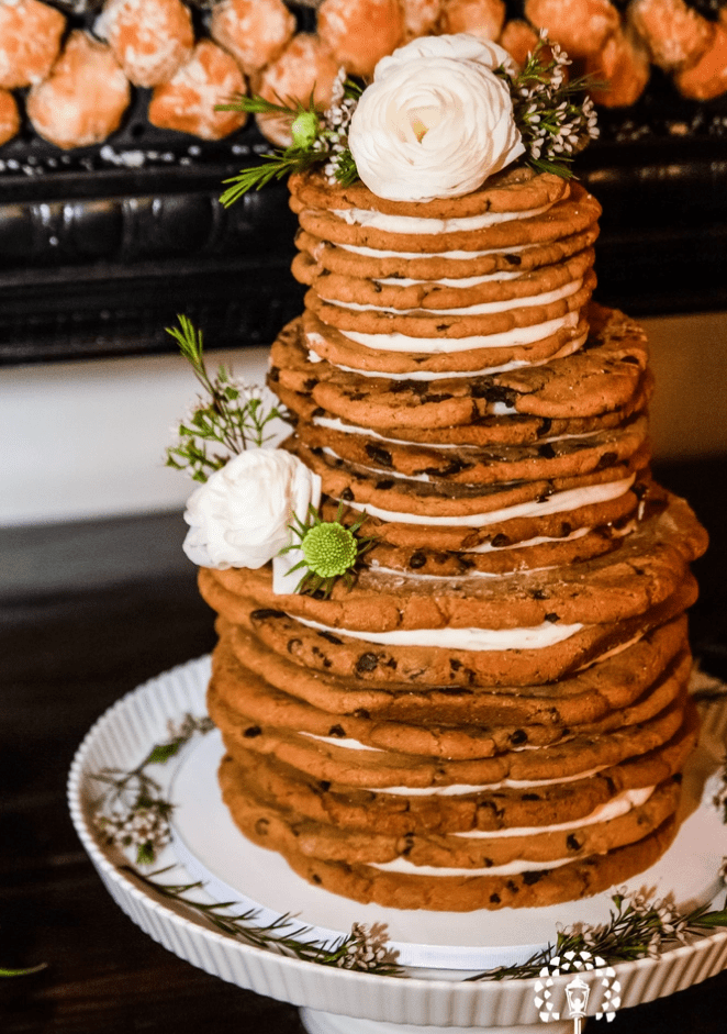 a chocolate chip cookie wedding cake with white filling, white blooms and greenery is a very cool idea