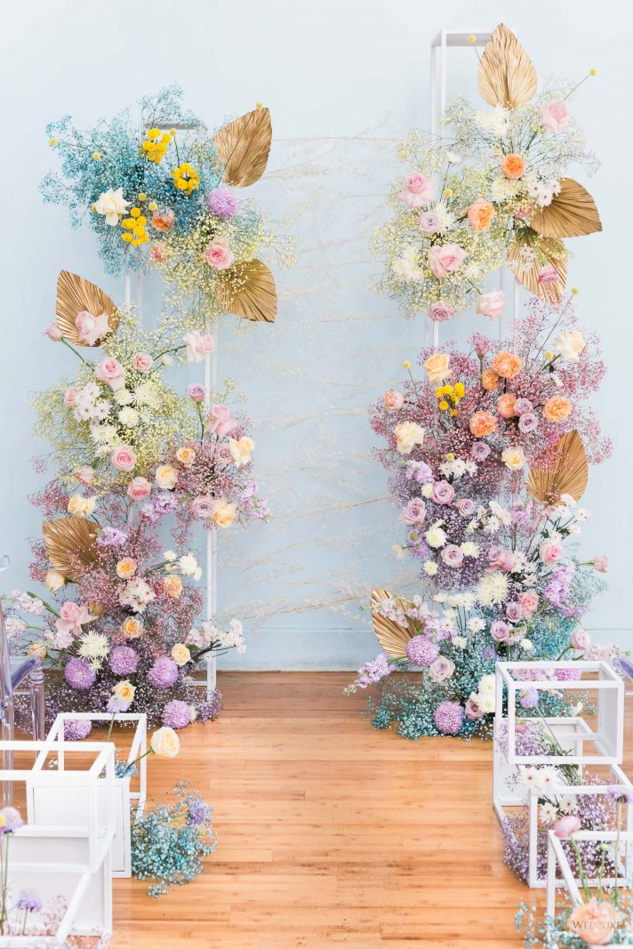 a jaw-dropping rainbow colored wedding altar of colorful baby's breath and spray painted palm leaves is all cool
