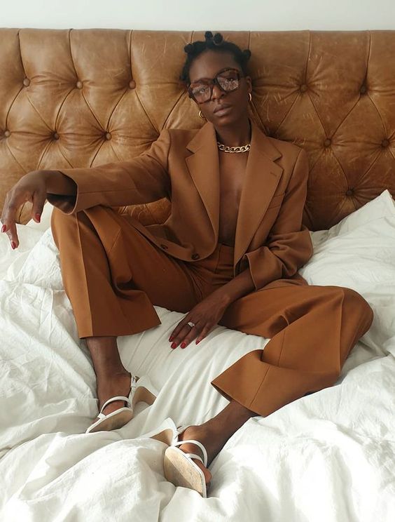 a rust-colored pantsuit, white slingbacks, a statement chain, gold earrings for a bold look