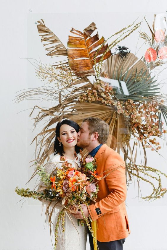 a boho wedding decoration with bold dried palm leaves, dried blooms and some tropical foliage is amazing