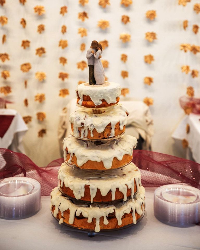 a multiple tier cinnamon bun wedding cake with white frosting and traditional toppers is pure delight