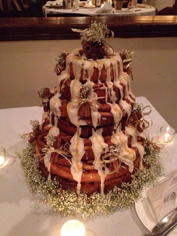 a simple cinnamon roll wedding cake with white icing, baby's breath and cinnamon sticks on top is beautiful
