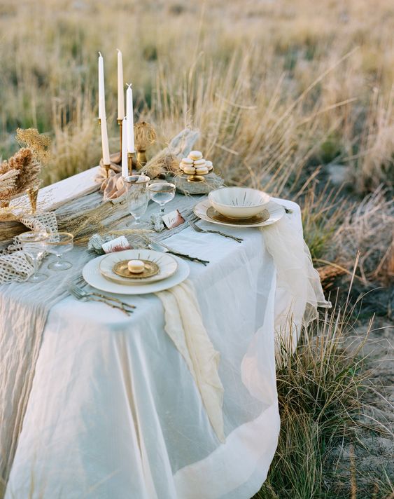 a pretty and refined Scandinavian spring tablescape with neutral linens, candles, chic porcelain, gold rimmed glasses
