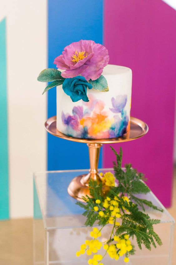 a white wedding cake with bright watercolors, bold blooms and painted leaves is a fun and colorful idea