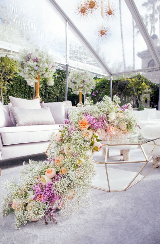 a refined wedding lounge with a runner of white and purple baby's breath and peachy peonies is all beautiful