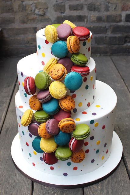 a white wedding cake decorated with colorful macarons and polka dots is a fabulous idea for a fun and cheerful wedding