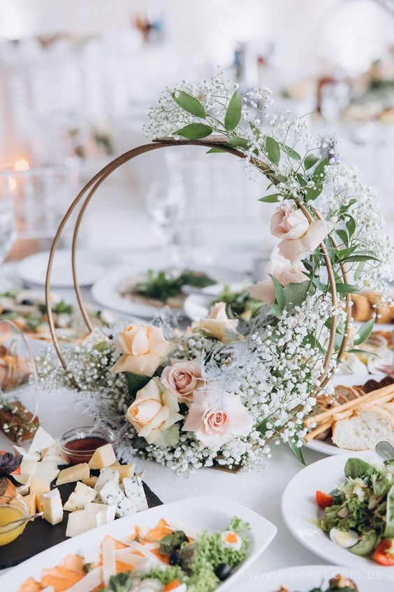 a refined double hoop wedding centerpiece with greenery, baby's breath and peachy and blush roses