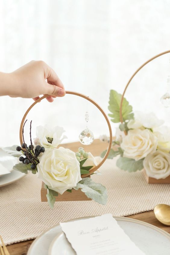 a simple and cute hoop centerpiece with some foliage, berries and white blooms plus a hanging crystal