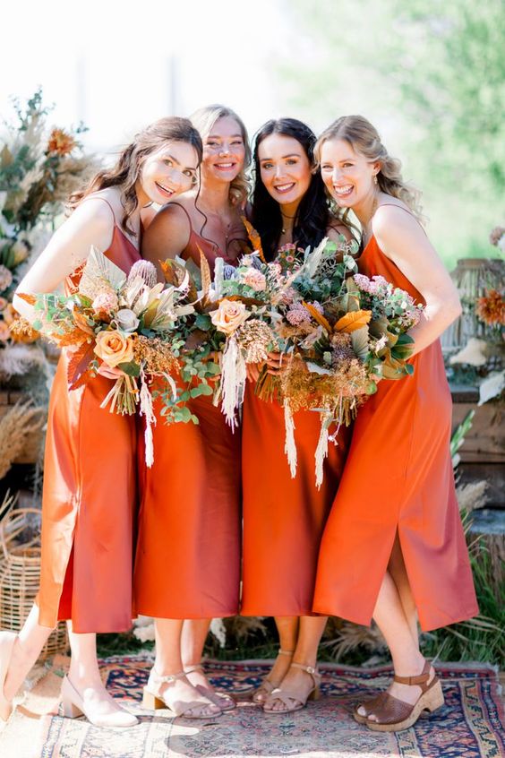 pretty burnt orange midi slip bridesmaid dresses with side slits paired with simple and platform sandals are chic for a boho wedding