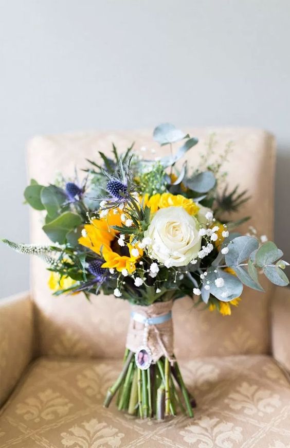 a bright and cool wedding bouquet with a white rose, sunflowers, thistles, baby's breath and eucalyptus is amazing