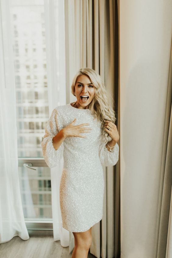 a beautiful white sequin mini sheath reception dress with a high neckline and long sleeves is a lovely and glam idea