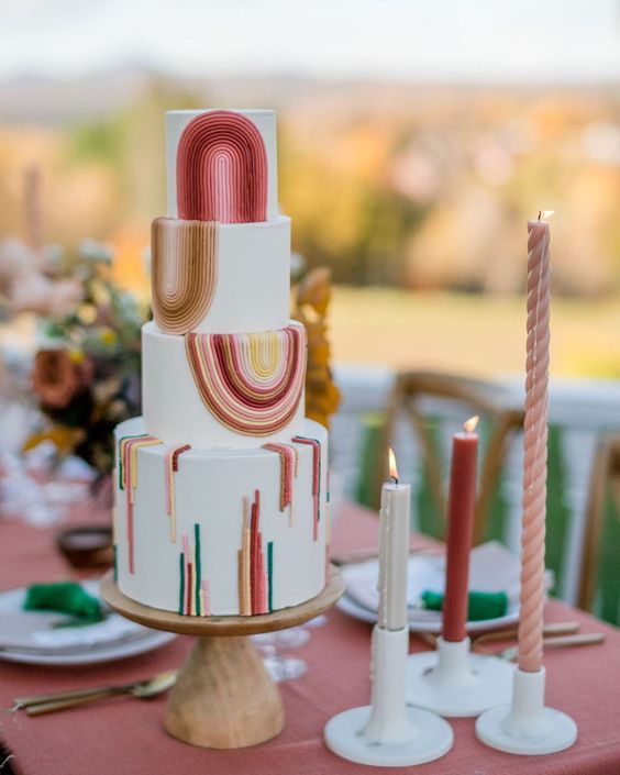 a lovely 70s wedding cake in white, with bold stripes and ribbons is a cool idea for a boho-inspired wedding