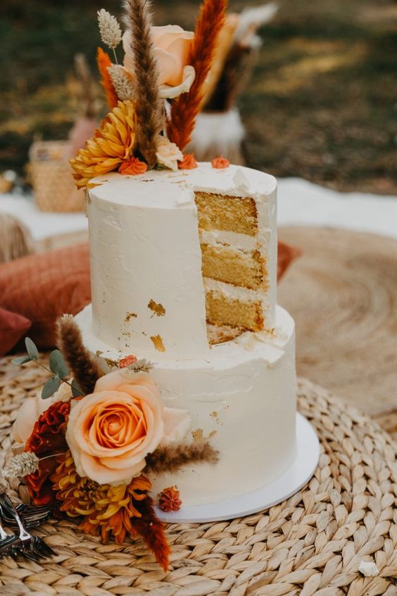 a beautiful boho wedding cake with bold and pastel blooms, eucalyptus, colorful grass is a stylish and bold idea for a 70s wedding