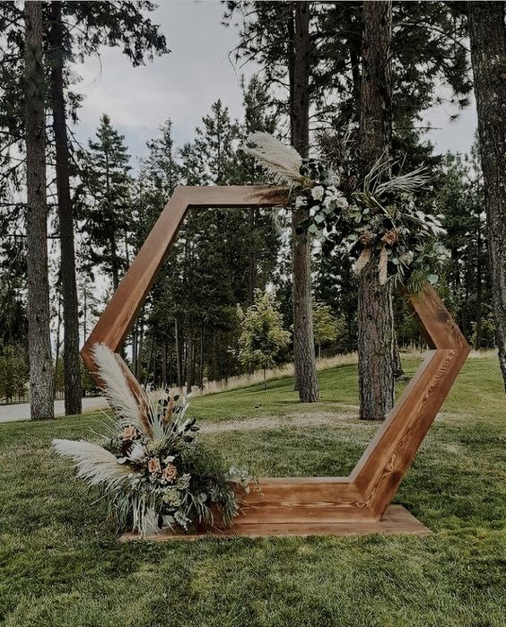 a boho hex wedding arch with greenery, white and blush blooms and pampas grass is a lovely idea for a boho wedding