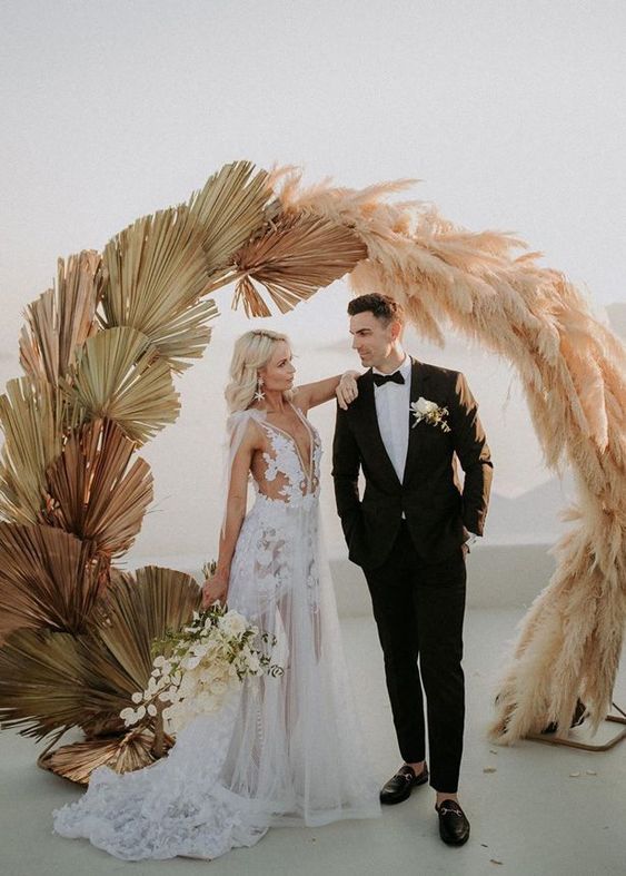 a gorgeous round wedding arch with fronds and pampas grass is a lovely idea for a boho wedding