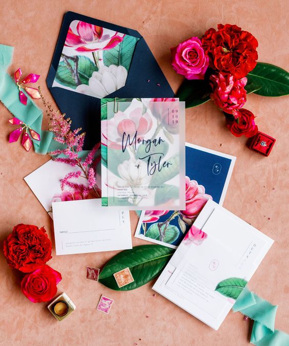 a modern colorful wedding invitation suite with bright floral prints and semi sheer invites is a bold and cool idea