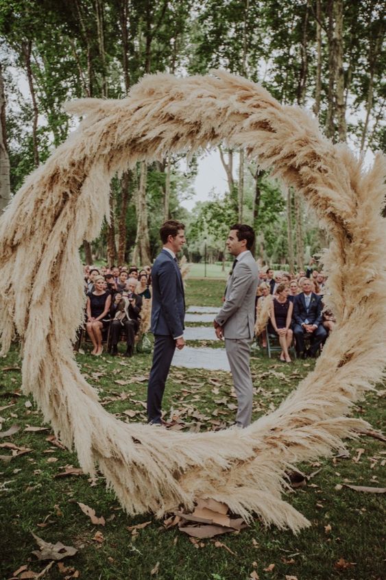 a round wedding arch decorated fully with pampas grass is a very pretty idea for a boho wedding