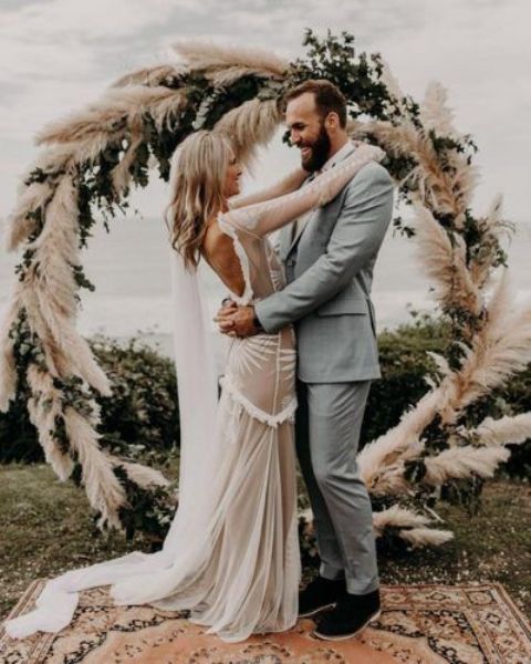 a round wedding arch done with greenery and pampas grass is a perfect idea for a boho wedding
