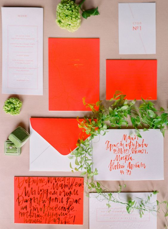 a super bright wedding invitation suite with neon red items and white ones for a contrast and bold and fun calligraphy