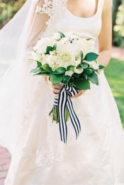 a nautical wedding bouquet composed of white dahlias and roses, with greenery and a striped ribbon is a gorgeous and classic idea