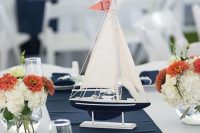 a beautiful nautical wedding centerpiece of white and rust blooms, a boat with a flag that is a table number