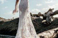 a boho celestial mermaid wedding dress with a cutout back, bell sleeves, a train and white embroidered stars all over the gown