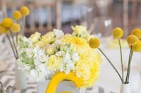 a bright spring or summer wedding centerpiece with a chevron runner, a yellow table number, bright yellow and white blooms, billy balls in vases