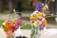 a bright wildflower wedding centerpiece of various colorful wildflowers and billy balls plus some fresh berries is lovely