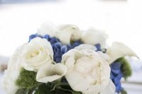 a chic nautical wedding centerpiece of white and blue blooms and foliage in a vase wrapped with rope