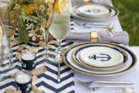 a chic nautical wedding tablescape with a chevron table runner, driftwood, neutral blooms and greenery, nautical plates and candles