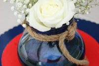 a classic nautical wedding centerpiece of a blue vase with rope, white roses and baby’s breath is a lovely and chic idea for a nautical wedding