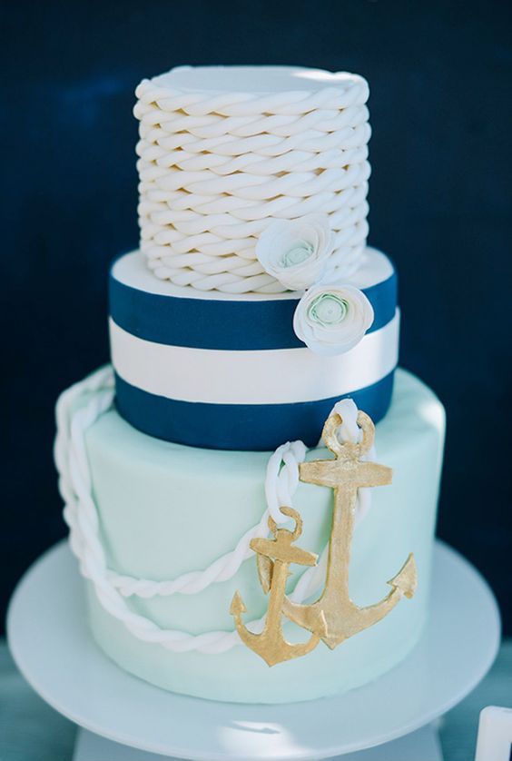 a cool nautical wedding cake with an aqua, a striped navy and a white rope tier, with ropes, sugar blooms and anchors