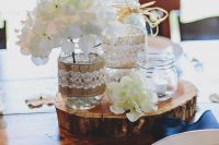 a country nautical wedding centerpiece of a wood slice, white blooms, jars with candles and blooms is amazing and always in trend