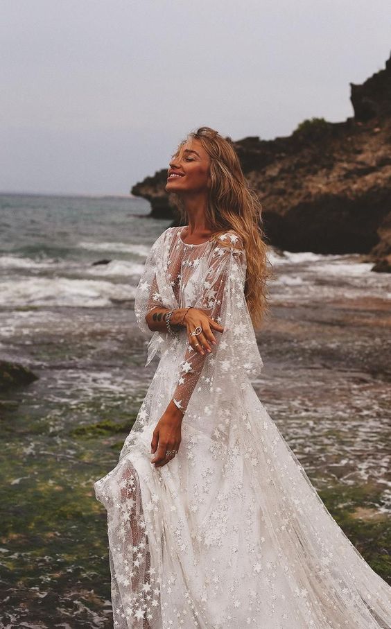 a dreamy celestial wedding dress with bell sleeves, an illusion neckline and stars all over the gown is just jaw-dropping
