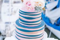 a funny and cheerful nautical wedding cake with white, pink and blue stripes, white and pink peonies and a rope piece with calligraphy