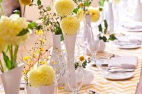 a gorgeous cluster wedding centerpiece of white vases, greenery, yellow dahlias and billy balls is amazing for spring