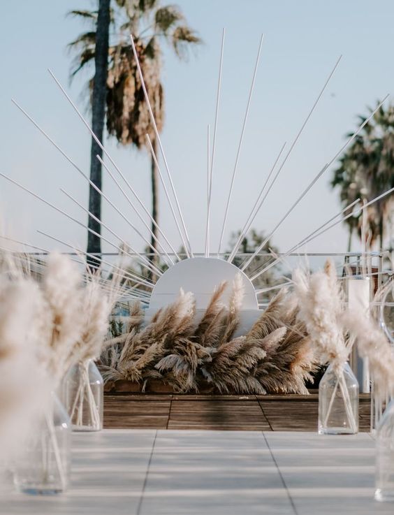 a mid-century modern boho wedding altar of sunbrust and lots of pampas grass is a fresh take on a mid-century modern piece
