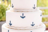 a nautical wedding cake in white with navy anchors, ropes, paper boat toppers for a touch of casual and fun