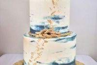 a nautical wedding cake with blue brushstrokes, some rope, gold leaf, a gilded anchor on top is amazing and chic